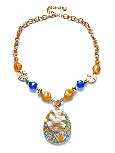 SA vibrant necklace featuring a gold chain with various beads in yellow, blue, and orange hues. In the center, a large teardrop-shaped pendant with a floral pattern in blue, orange, and yellow, partially overlaid with a hammered gold disc.