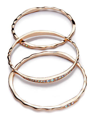Three rose gold bangles are arranged overlapping each other. Two have smooth, wavy edges, and the middle bangle is adorned with small, iridescent stones in a row. All have a polished finish against a white background.