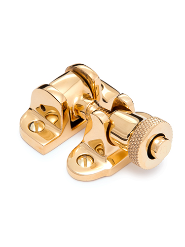 A shiny brass latch with a cylindrical knob and two screw holes on each base, designed for securing windows. The latch features a polished finish and intricate detailing on the knob for grip.